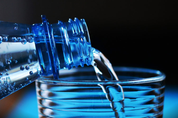 blue background with bottle of water being poured into a glass