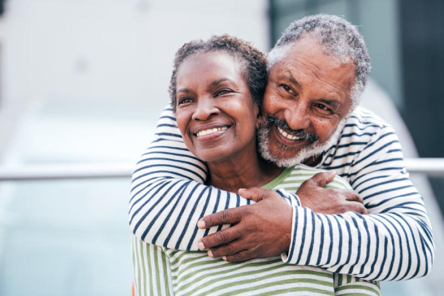 Smiling older black man with his arms around a smiling woman. 