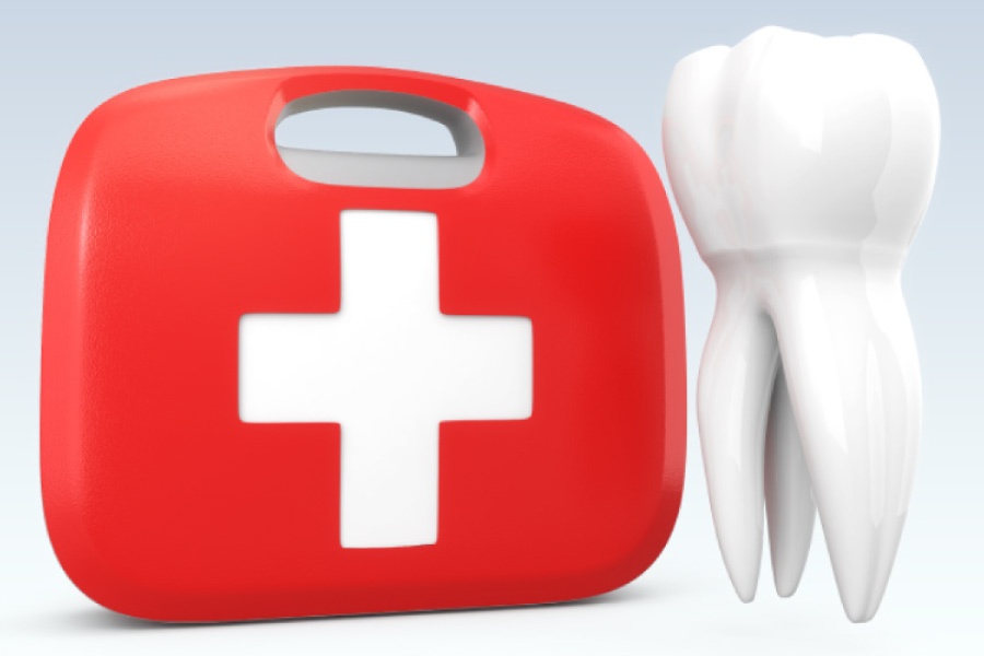 A red emergency kit with a white cross sitting next to a model of a tooth.