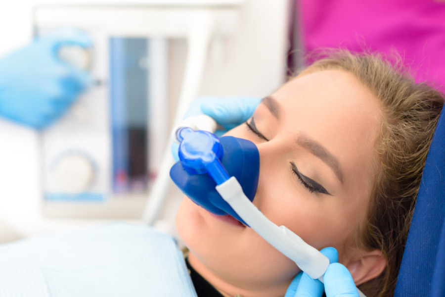 Woman in the dental chair with a mask on to deliver nitrous oxide to manage dental anxiety.