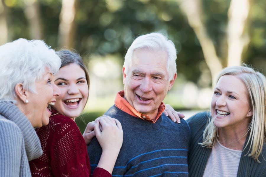 Senior couple chatting outside with a daughter and granddaughter.