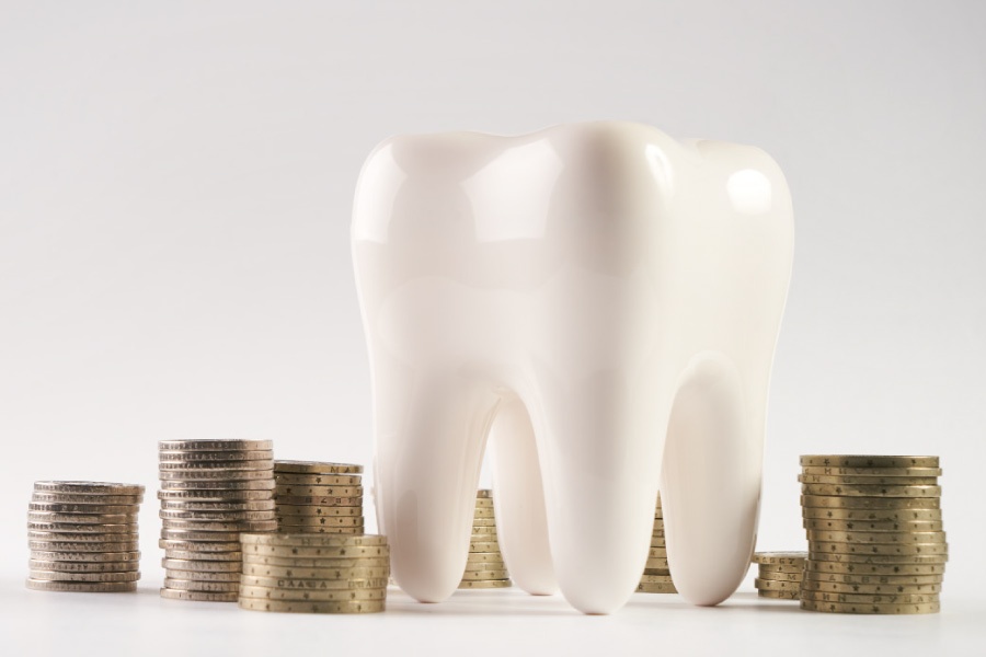 A large model of a tooth next to stacks of coins.